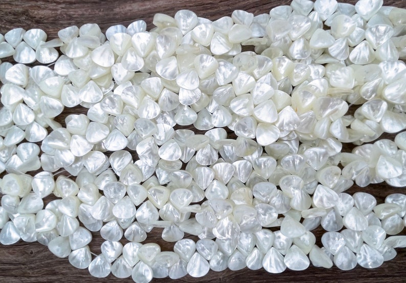 May include: A strand of white iridescent shell beads in a triangular shape. The beads are arranged in a random pattern and are all the same size.