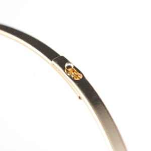 Puede incluir: Un brazalete de metal dorado con un peque&ntilde;o cierre redondo.