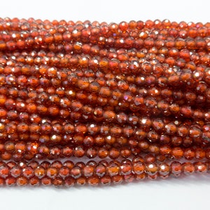 May include: A strand of small, faceted, red-brown gemstone beads. The beads are round and have a shiny, iridescent finish.