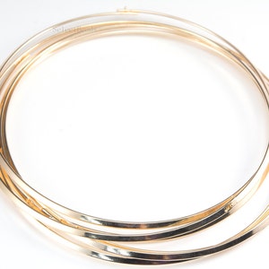 May include: Three gold-colored metal hoops, stacked on top of each other, forming a circle.