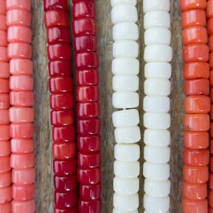 Puede incluir: Seis hebras de cuentas en varios tonos de rosa, rojo y blanco. Las cuentas son todas de forma cuadrada y tienen un acabado brillante.
