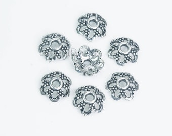 May include: Seven silver-toned metal bead caps with a flower design. Each cap has a small hole in the center.