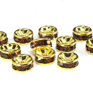 May include: Ten gold-toned metal bead caps with a row of brown rhinestones around the edge.