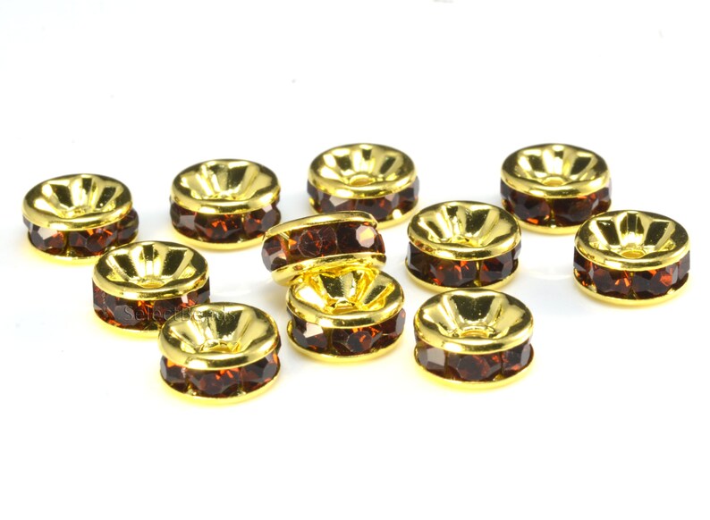 May include: Ten gold-toned metal bead caps with a row of brown rhinestones around the edge.