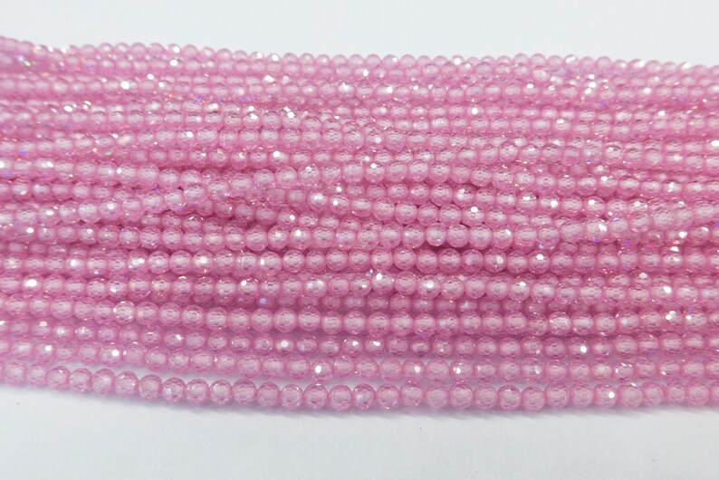 May include: A strand of pink crystal beads. The beads are round and have a faceted finish. The beads are strung on a clear thread.