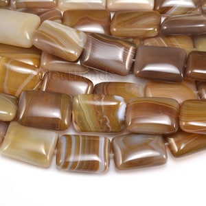 May include: A strand of brown, beige, and white agate gemstone beads. The beads are rectangular and have a smooth, polished finish.