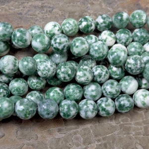 May include: A strand of green and white agate beads. The beads are round and have a speckled pattern.