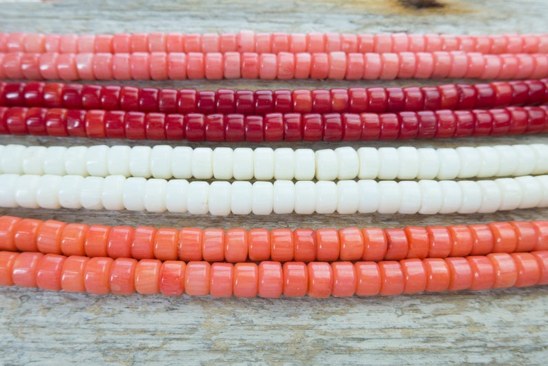 Puede incluir: Cuatro hebras de cuentas de coral en diferentes tonos de rosa, rojo y blanco. Las cuentas son redondas y tienen un acabado liso y pulido.