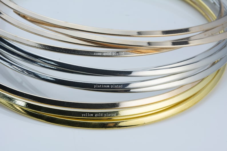 Puede incluir: Primer plano de tres bandas met&aacute;licas, una etiquetada "chapado en oro amarillo", otra "chapado en platino" y la &uacute;ltima "chapado en oro rosa".
