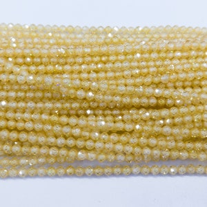 May include: A strand of small, round, faceted beads in a light yellow color. The beads have a slight iridescent shimmer.