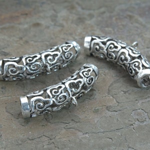 Pode incluir: Tr&ecirc;s tampas de contas de metal prateado com um design decorativo de nuvens. As tampas s&atilde;o abertas em ambas as extremidades e s&atilde;o projetadas para serem usadas como tampas finais para colares ou pulseiras.
