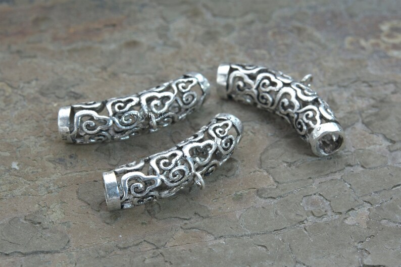 Pode incluir: Tr&ecirc;s tampas de contas de metal prateado com um design decorativo de nuvens. As tampas s&atilde;o abertas em ambas as extremidades e s&atilde;o projetadas para serem usadas como tampas finais para colares ou pulseiras.