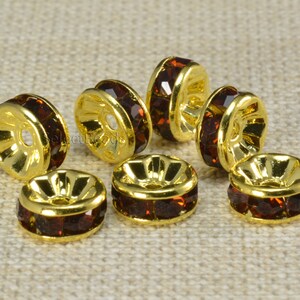 May include: Eight gold-toned metal bead caps with a single row of dark brown rhinestones around the edge.