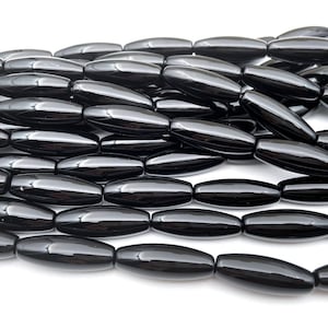 May include: A strand of black onyx beads, each bead is a smooth, oval shape.