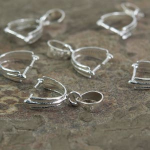 May include: Silver pendant bail clasps, a type of jewelry finding, with a smooth, shiny finish. These clasps are designed to hold a pendant securely to a chain or cord.