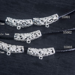 以下が含まれることがあります： 花柄の銀色の金属製のコードエンドが3つ。各エンドは28mm×8mmで、5mmの穴が開いています。コードエンドは、SS001、SS002、SS003とラベル付けされた黒いコードに表示されています。