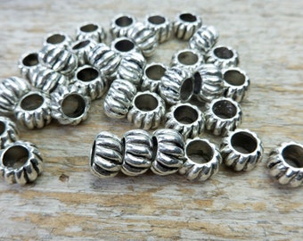 May include: A pile of silver metal beads with a rope-like design. The beads are about 1 inch in diameter and have a hole in the center.