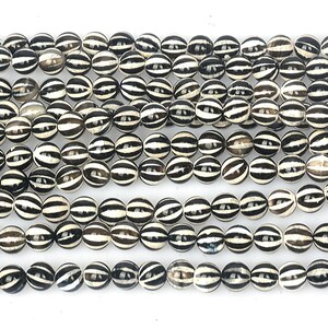 May include: A strand of black and white striped agate beads. The beads are round and have a smooth, polished finish.