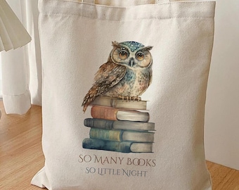 Puede incluir: Un bolso tote beige con una ilustración detallada de un búho posado sobre una pila de libros. El búho tiene plumas marrones y azules y ojos grandes. El texto "SO MANY BOOKS SO LITTLE NIGHT" está impreso debajo.