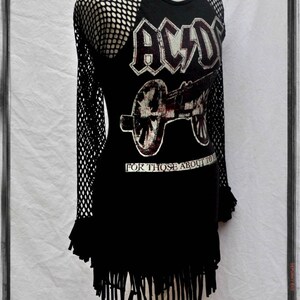 May include: Black t-shirt with a mesh overlay on the sleeves. The shirt features a graphic of a cannon and the text "AC/DC" and "For Those About To Rock".