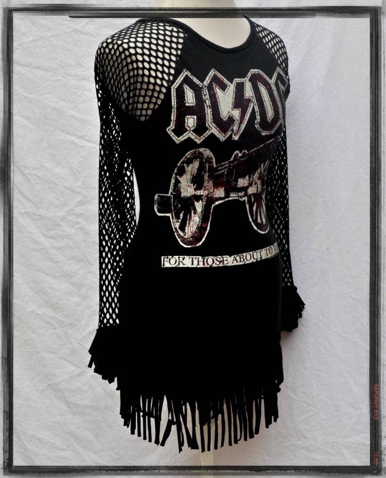 May include: Black t-shirt with a mesh overlay on the sleeves. The shirt features a graphic of a cannon and the text "AC/DC" and "For Those About To Rock".