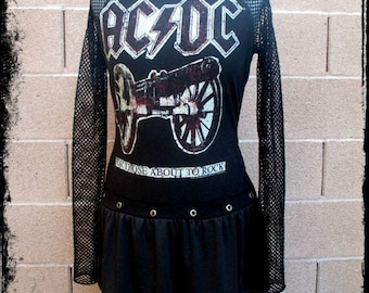 May include: Black long-sleeved shirt with a mesh overlay. The shirt features a graphic of a cannon and the text "AC/DC" and "For Those About To Rock".
