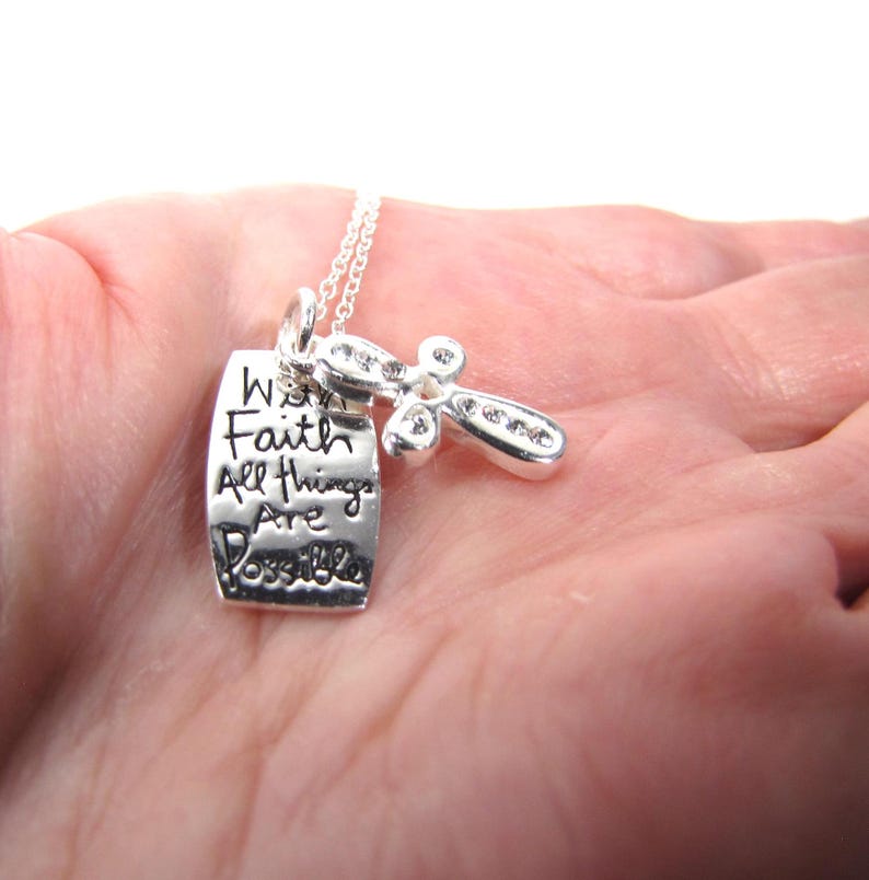 Puede incluir: Collar de plata con un dije de cruz y un dije rectangular que dice "With Faith All Things Are Possible".
