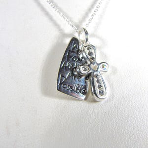 Puede incluir: Collar de plata con un colgante que dice "Con fe todo es posible" y una peque&ntilde;a cruz con pedrer&iacute;a.