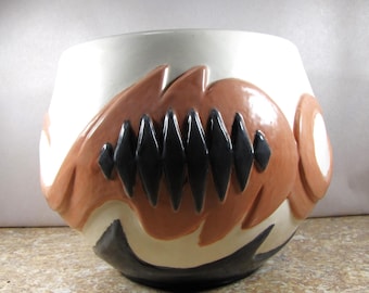 May include: A white ceramic planter with a brown and black abstract design. The planter has a wide, rounded base and a slightly flared rim.