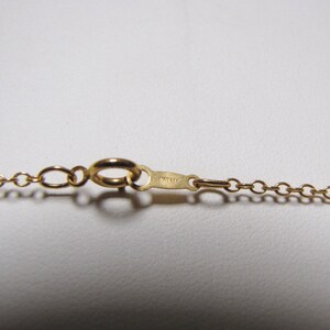 May include: A gold chain necklace with a lobster clasp closure. The clasp has the inscription "12K GF" on it.