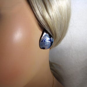May include: A silver and blue glass earring with a swirl design.