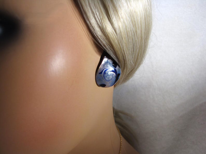 May include: A silver and blue glass earring with a swirl design.