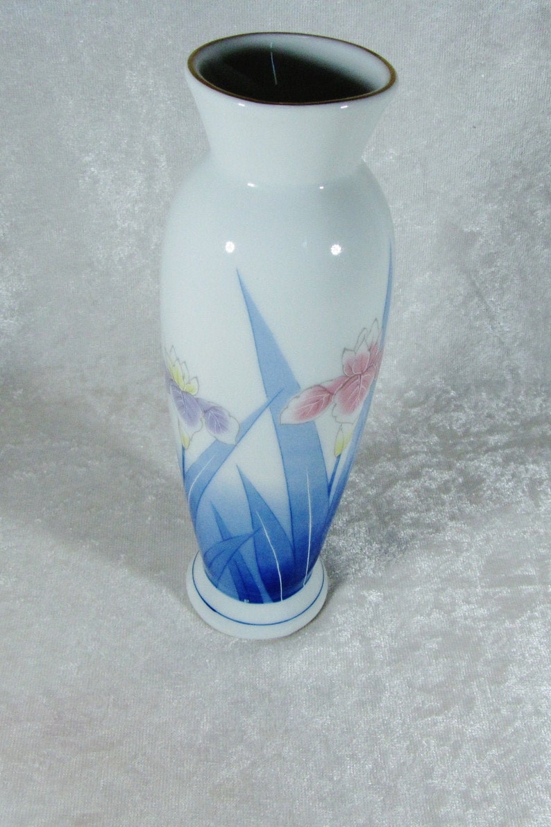 May include: A white porcelain vase with a blue and white floral design. The vase has a rounded body and a flared top.