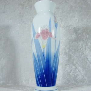 May include: A white ceramic vase with a blue and white floral design. The vase features a pink and white iris with blue leaves.