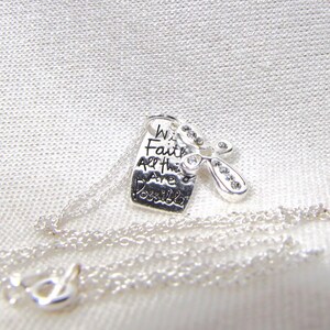 Puede incluir: Collar de plata con un dije que dice "Con fe todo es posible" y una peque&ntilde;a lib&eacute;lula de plata con brillantes transparentes.