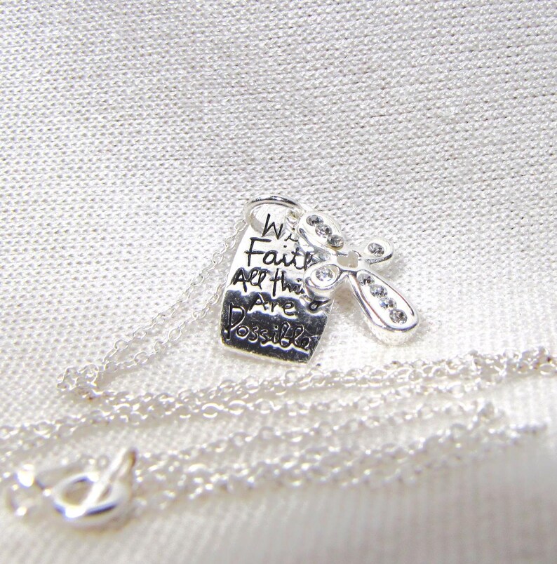 Puede incluir: Collar de plata con un dije que dice "Con fe todo es posible" y una peque&ntilde;a lib&eacute;lula de plata con brillantes transparentes.
