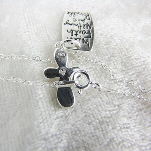 Puede incluir: Un collar de plata con un colgante de cruz y un peque&ntilde;o dije en forma de coraz&oacute;n. La cruz tiene la inscripci&oacute;n "925" en la parte posterior. El collar tambi&eacute;n tiene una peque&ntilde;a etiqueta con la inscripci&oacute;n "Con fe puedes hacer cualquier cosa posible".