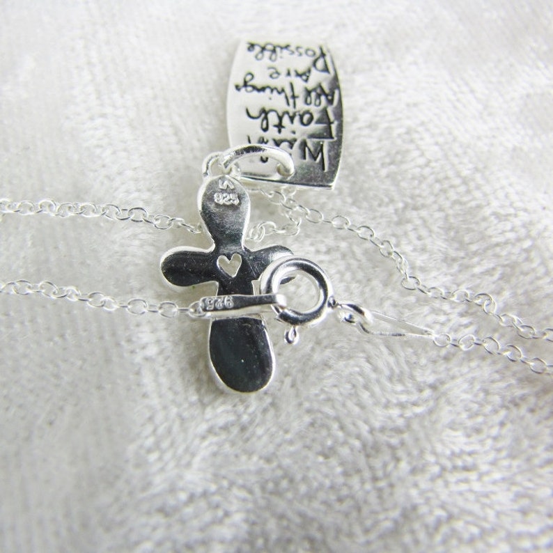 Puede incluir: Un collar de plata con un colgante de cruz y un peque&ntilde;o dije en forma de coraz&oacute;n. La cruz tiene la inscripci&oacute;n "925" en la parte posterior. El collar tambi&eacute;n tiene una peque&ntilde;a etiqueta con la inscripci&oacute;n "Con fe puedes hacer cualquier cosa posible".
