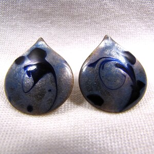 May include: A pair of silver and blue enamel earrings with a teardrop shape and black swirl designs.