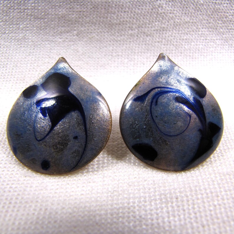 May include: A pair of silver and blue enamel earrings with a teardrop shape and black swirl designs.