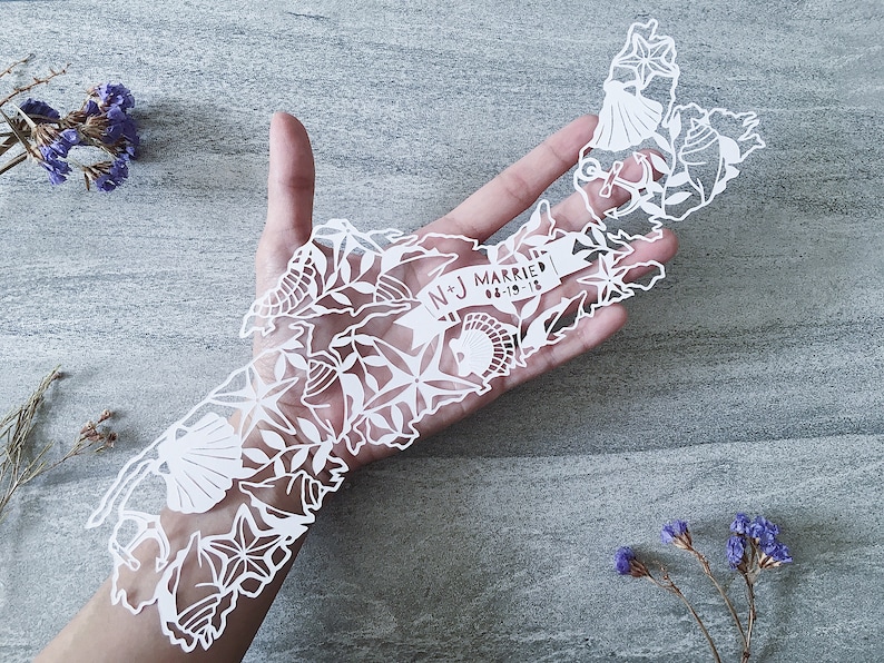 May include: White paper cut-out of the state of Massachusetts with a banner that reads "N+J Married 06-19-18" and various nautical and floral designs.