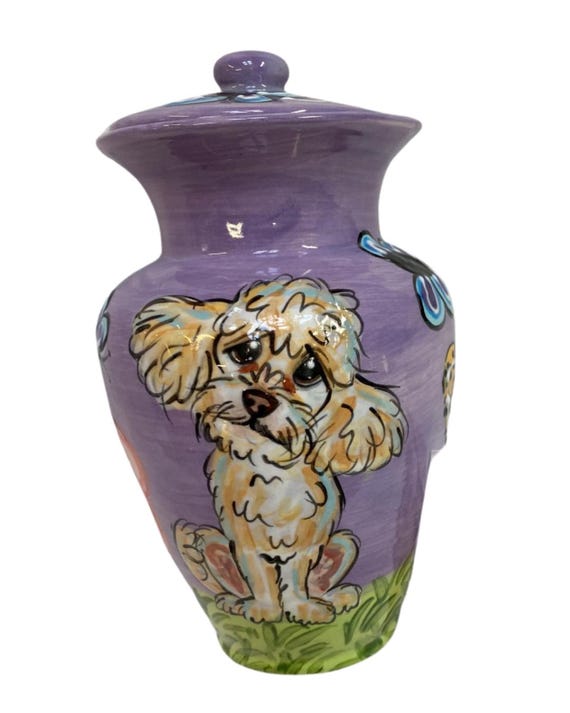 Hand-painted ceramic urn depicting YOUR specific dog breed — an apricot poodle, pug, or yorkie rendered in portrait — this is museum-quality grief art.