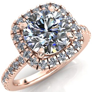 May include: A rose gold engagement ring with a large, round, clear center stone surrounded by a double halo of smaller, clear stones.