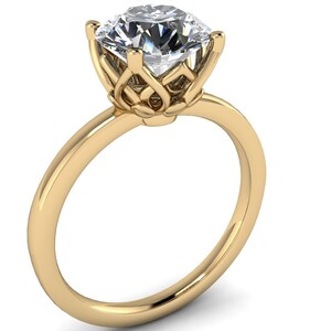 May include: A gold engagement ring featuring a large, clear, round diamond set in a delicate, intricate, floral-inspired design.