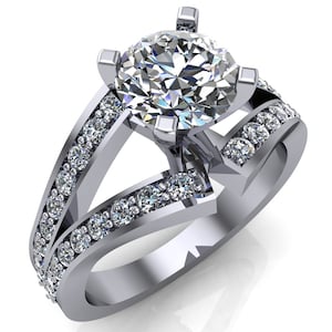 Puede incluir: Un anillo de compromiso de plata con un gran diamante redondo central y diamantes más pequeños engastados en pavé en la banda.