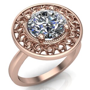 May include: A rose gold ring featuring a large, round, clear diamond set within a delicate, filigree design.