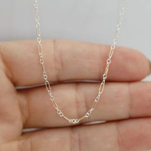 May include: A delicate necklace chain featuring an alternating pattern of elongated oval links and small circular links. The chain is constructed from a combination of silver-toned metal and gold-toned metal, creating a two-tone metallic appearance.