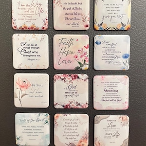 May include: A collection of twelve square magnets with inspirational quotes and floral designs. Each magnet features a different message, such as "Faith, Hope, Love" and "I can do all things through Christ." The magnets are white with colorful floral borders.