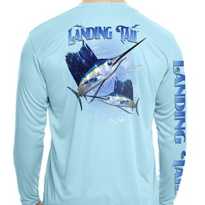 May include: Light blue long-sleeved shirt with a graphic of two sailfish jumping out of the water. The shirt has the text "Landing Tail" on the back and the sleeve.