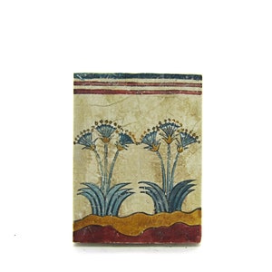 May include: A rectangular tile with a painted design of two blue and yellow papyrus plants on a beige background. The tile has a red and blue border.